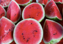 photo of cut open watermelons, showing their red insides and the occasional black seed