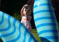 A five-year-old girl holding a camera is seen through the blue striped ears of a giant bunny