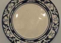 Dedham Pottery was famous for its off-white, crackled glaze plateware with a bright band of blue and white figures around the edge.
