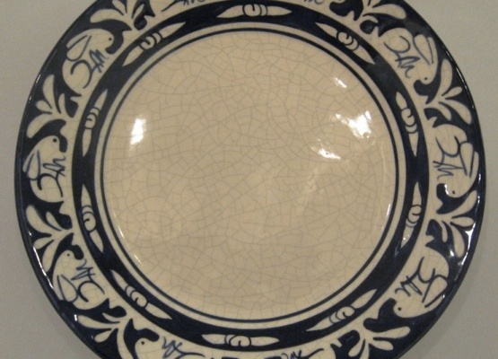 Dedham Pottery was famous for its off-white, crackled glaze plateware with a bright band of blue and white figures around the edge.