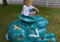 The Five-Year-Old sits on top of a teal-colored bunny painted all over with birds and flowers.