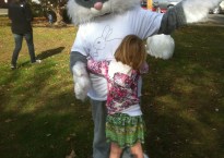 A small girl hugs a person in a giant rabbit suit.
