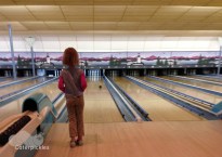 A six-year-old girl watches her bowling ball roll down a candlepin lane.