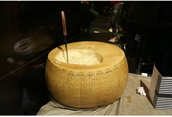A wheel of Grana Padano cheese with a cheese knife sticking out of its top.