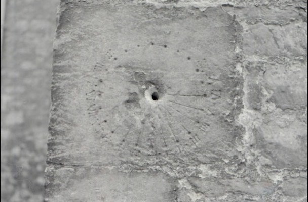 The medieval sundial looks like a hole in a stone wall surrounded by scratches in a circle at regular intervals.