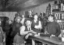 In this black and white photo, miners wait as the store manager weighs out their gold dust.