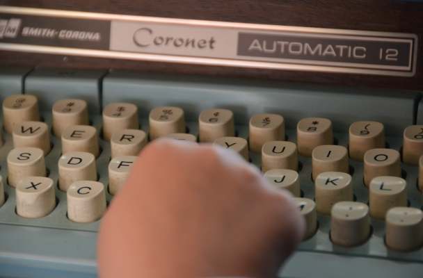 a child's hands pecks at the keys of an old Smith-Corona Coronet typewriter.