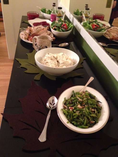 Serving platters and bowls of food spread out along a very long table. 