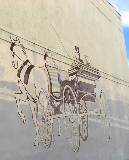 Horse and carriage painted in brown and white on the side of a building in downtown Palo Alto, CA