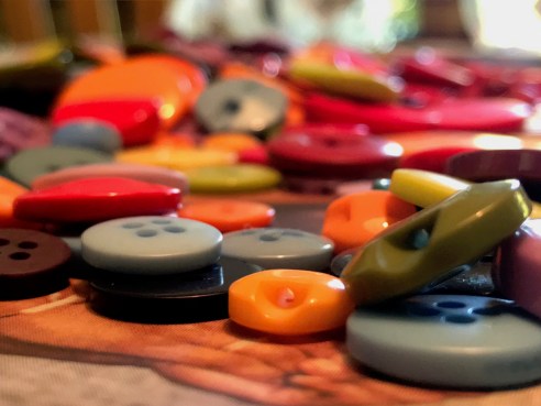 a pile of orange, blue, green, and red buttons on a crafting table