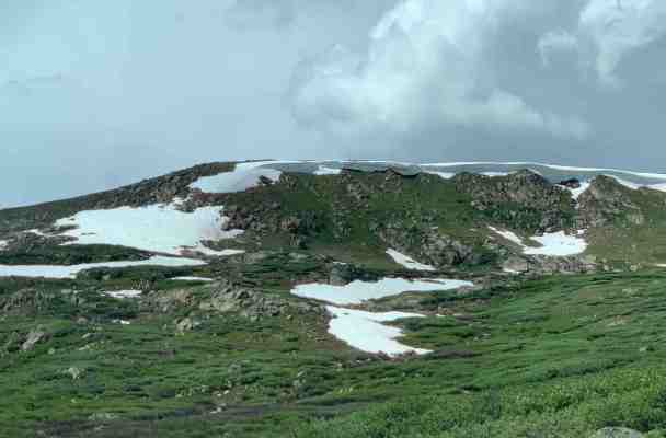 Photo of the top of the Rockies. It's mostly green, but there is some snow.