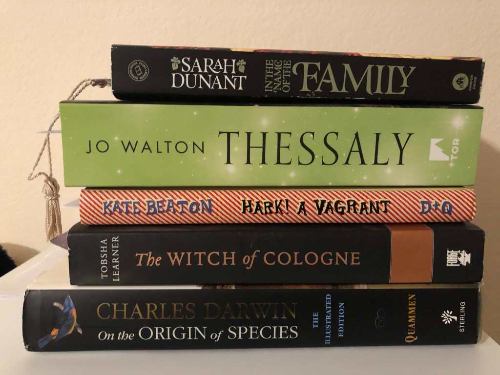 A pile of five books: The Illustrated Edition of Charles Darwin's On the Origin of the Species by David Quammen, The Witch of Cologne by Tobsha Learner, Hark! a Vagrant by Kate Beaton, Thessaly by Jo Walton, and In the Name of the Family by Sarah Dunant.