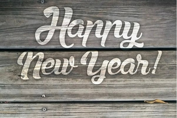 Image shows a wooden fence with the words Happy New Year! written on it in fat white letters.