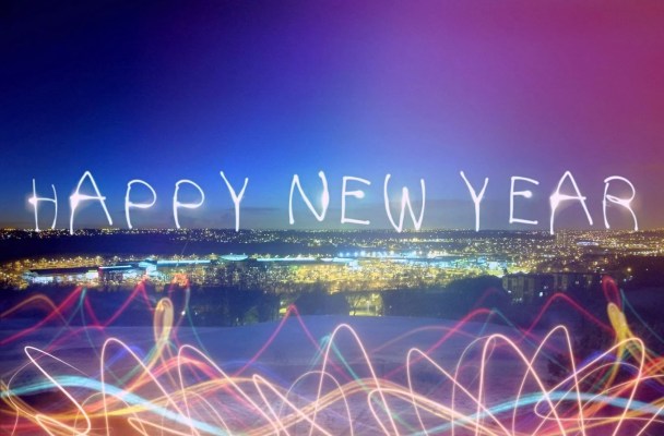 Photo shows a city skyline in lights. The words Happy New Year appear in a font that looks like it's made of light across the horizon.